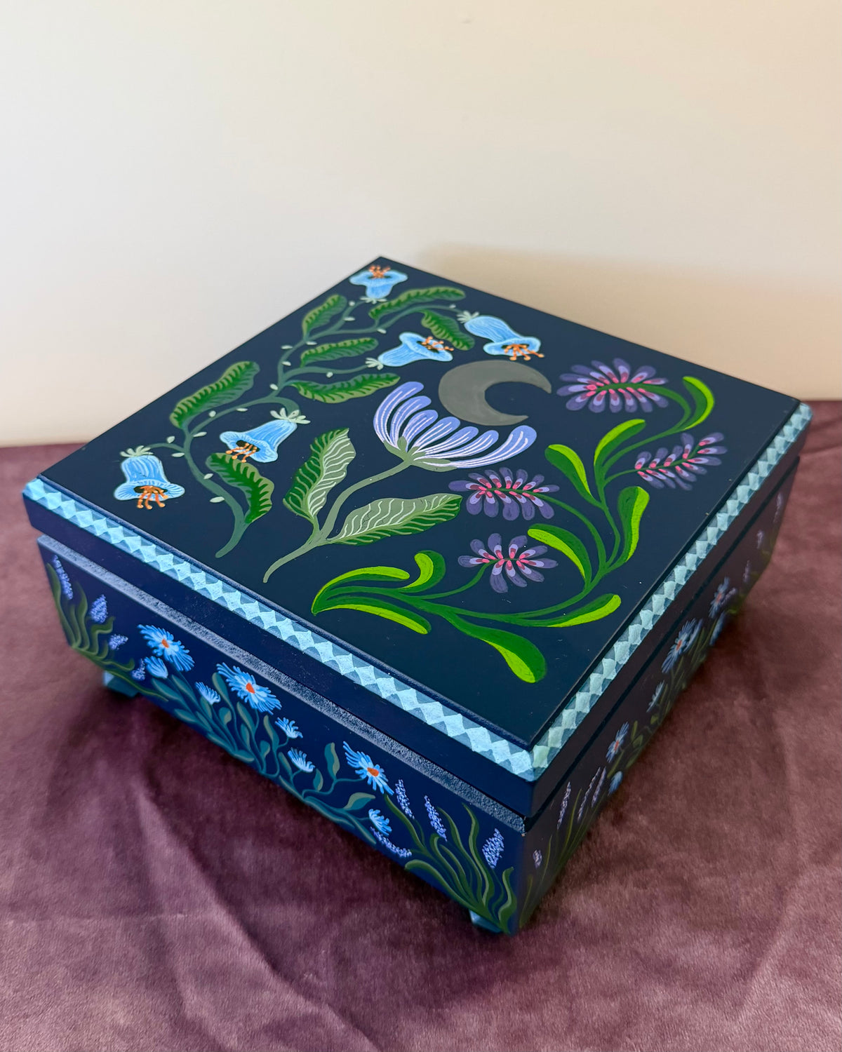 donkerblauwe sieradendoos met blauwe en paarse bloemen 