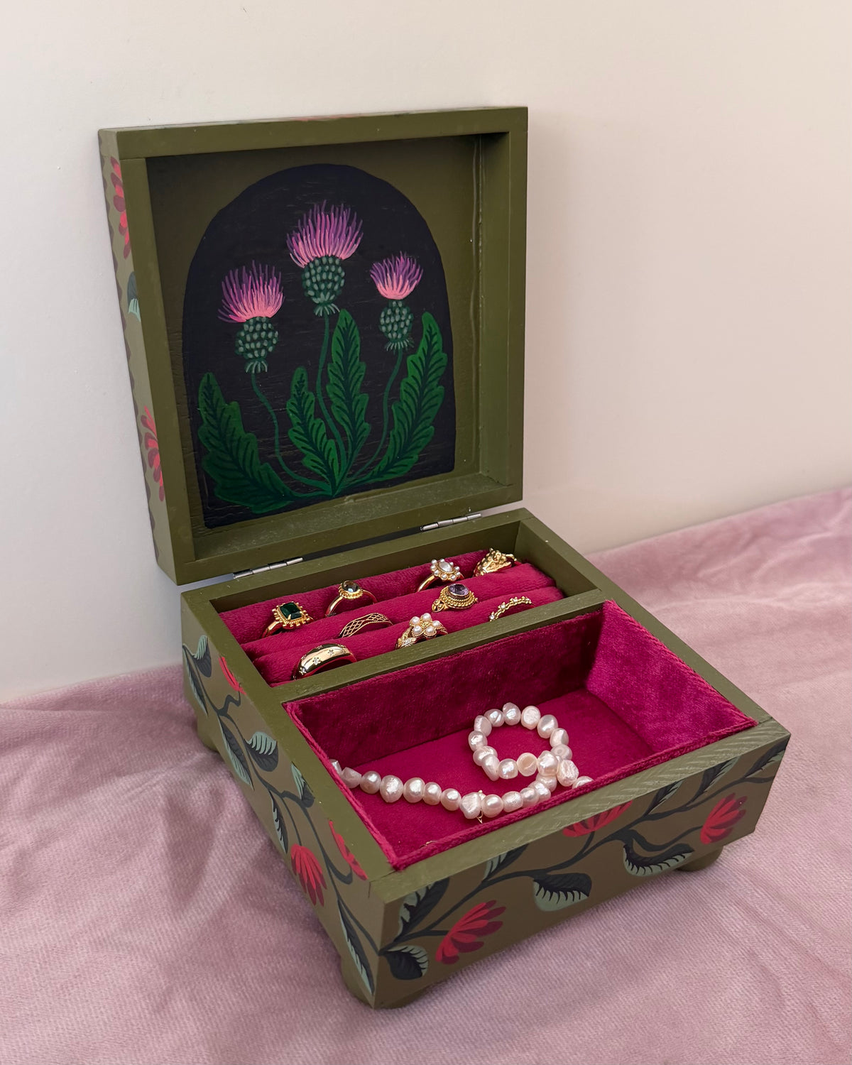 Grone sieradenkist met rode bekleding en roze bloemen
