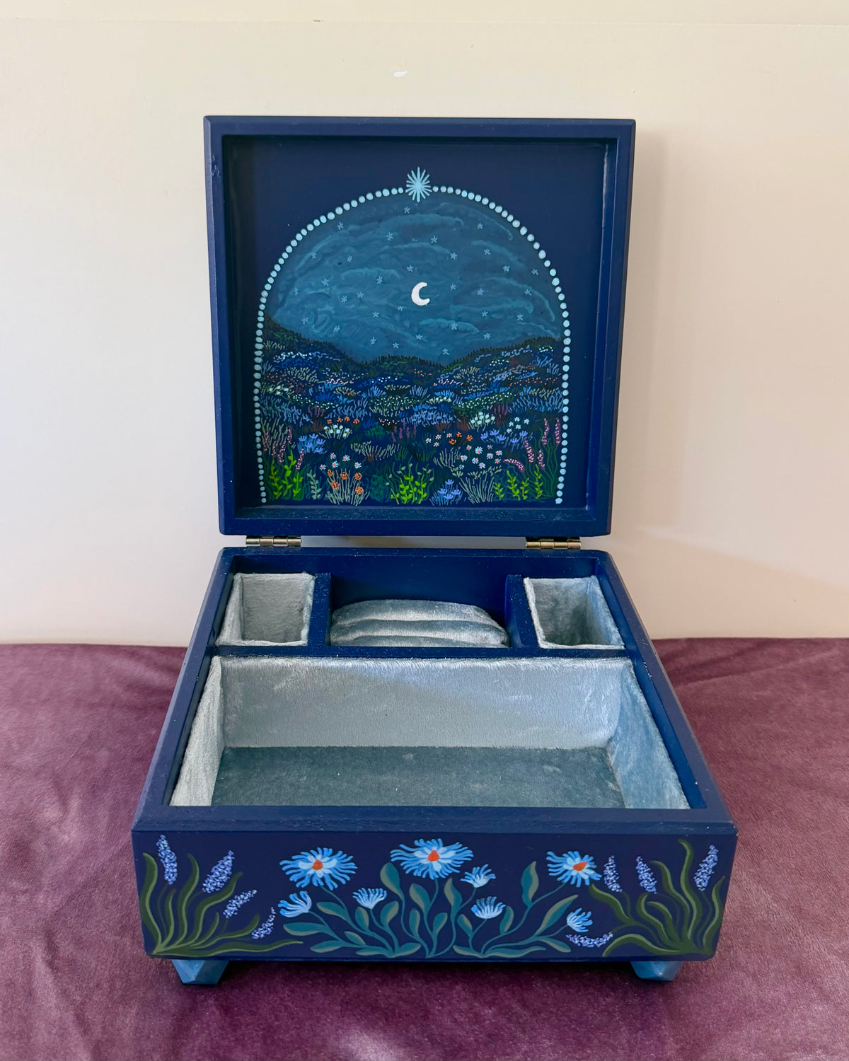 donkerblauwe sieradendoos met bloemenlandschap beschildering en blauw fluweel bekleding